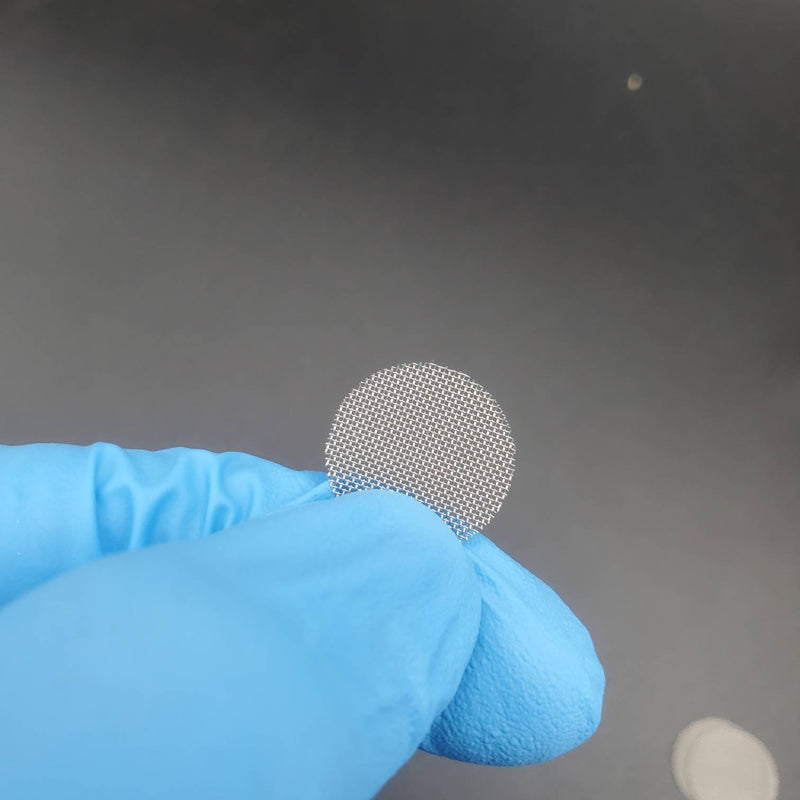 A close-up of a round stainless steel pipe screen held by a gloved hand, emphasizing the mesh texture.