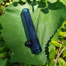 A transparent-blue mini glass chillum on a green leaf