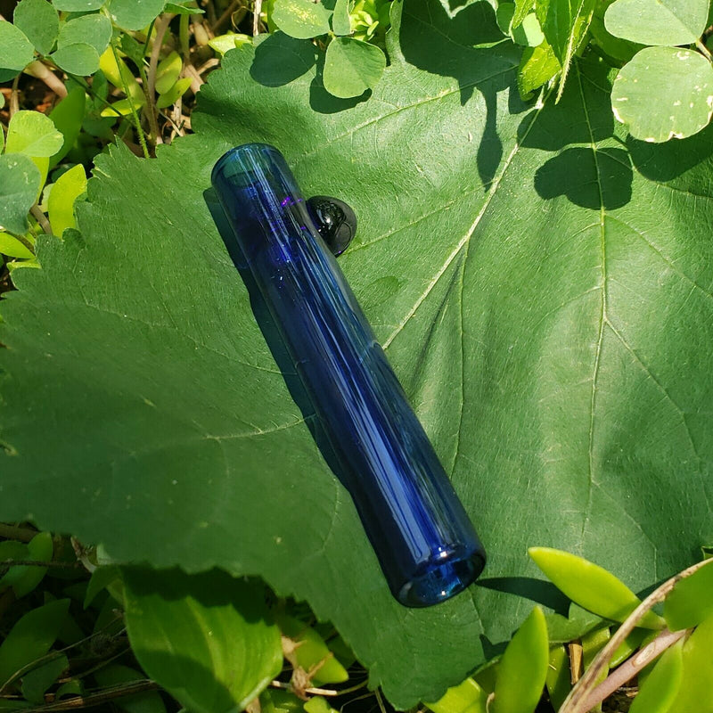 A transparent-blue mini glass chillum on a green leaf