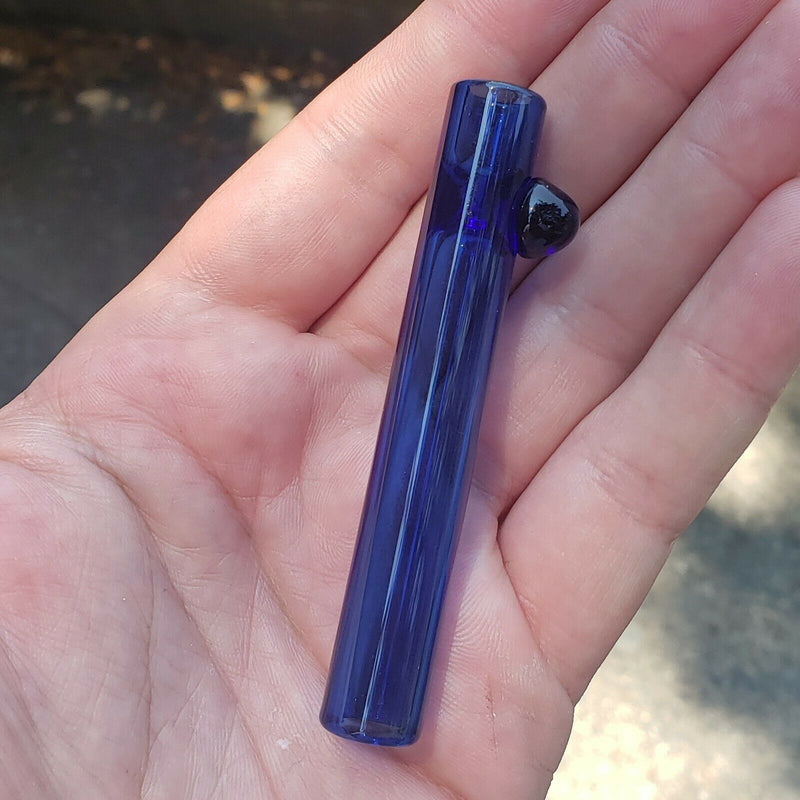 A transparent-blue mini glass chillum in a hand
