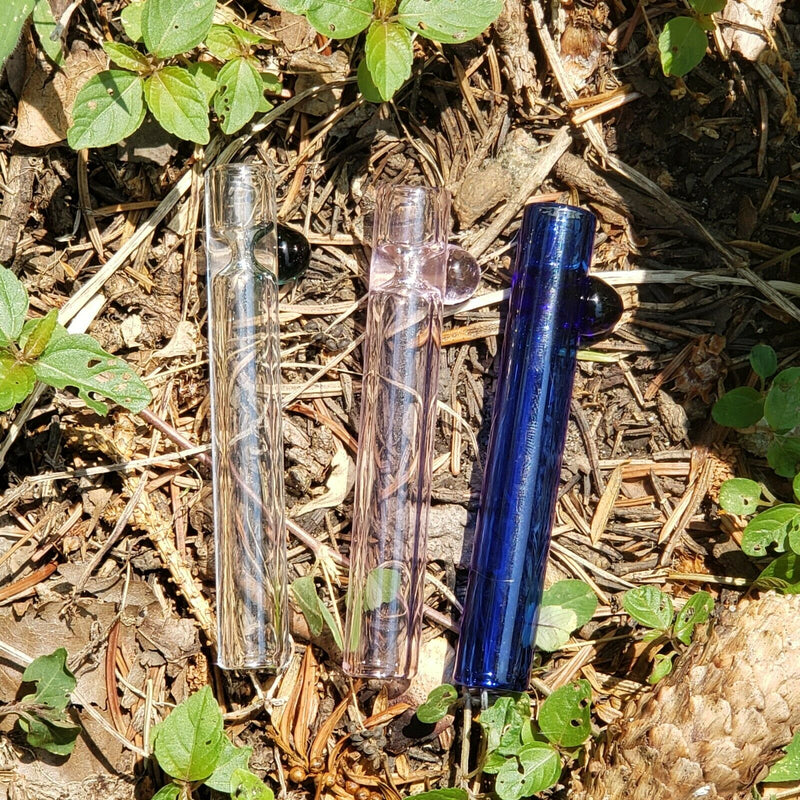 three mini glass chillum on some branches in diferent colors (transparent-white, transparent-pink, transparent-blue)
